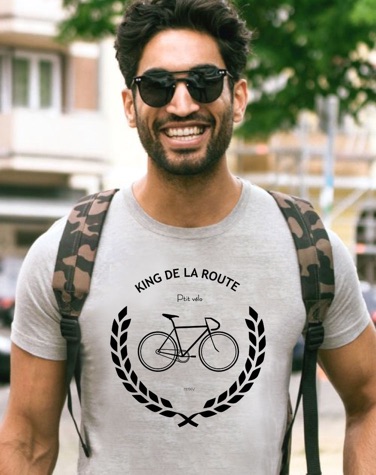 Man wearing a light grey T-shirt with a bicycle motif and the words King de la route